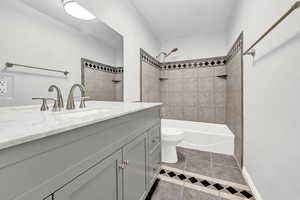 Full bathroom with toilet, vanity, tiled shower / bath, and tile patterned flooring