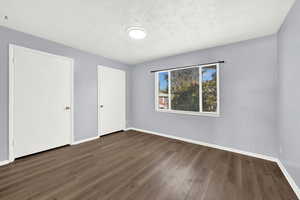 Unfurnished bedroom with a textured ceiling and dark hardwood / wood-style flooring