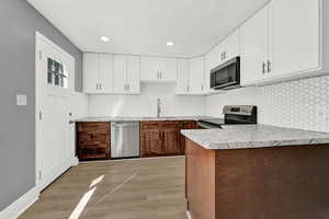 Kitchen with sink, white cabinets, light hardwood / wood-style flooring, and stainless steel appliances