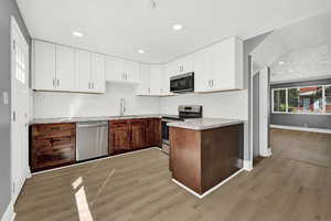 Kitchen with sink, white cabinets, light hardwood / wood-style flooring, and stainless steel appliances