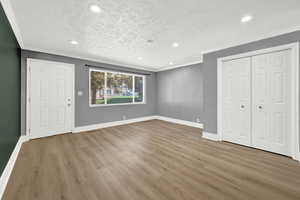 Unfurnished bedroom with a closet, crown molding, a textured ceiling, and hardwood / wood-style flooring