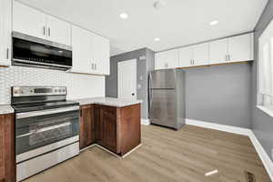 Kitchen featuring tasteful backsplash, white cabinets, and stainless steel appliances