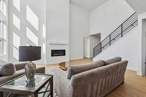 Living room with light wood-type flooring and a towering ceiling