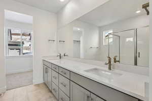 Bathroom with an enclosed shower, vanity, and tile patterned flooring