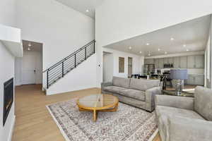 Living room with a high ceiling and light hardwood / wood-style floors