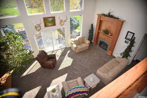 Living room featuring a tiled fireplace, a towering ceiling, and carpet flooring