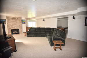 Carpeted living room with a brick fireplace and a textured ceiling