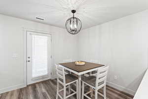 Dining area with a notable chandelier and dark hardwood / wood-style flooring