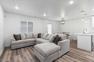 Living room with a notable chandelier, sink, and hardwood / wood-style floors