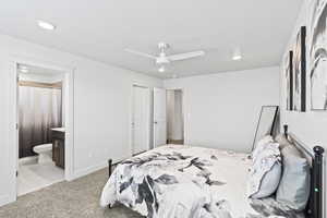 Carpeted bedroom with ceiling fan, a closet, and ensuite bath