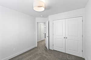 Unfurnished bedroom featuring a closet and dark colored carpet