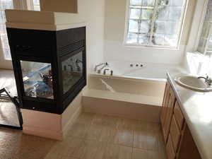 Bathroom with tile patterned flooring, a relaxing jetted tub, and vanity