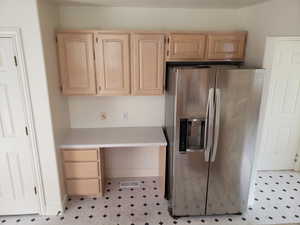 Kitchen with light brown cabinets and stainless steel fridge