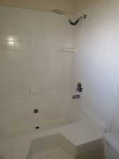 Bathroom with toilet and tiled shower / bath