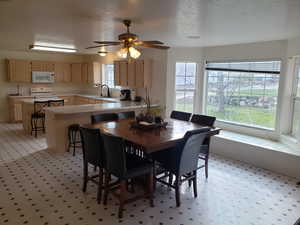 Dining room with ceiling fan, sink, and a healthy amount of sunlight