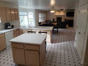 Kitchen with ceiling fan, dishwasher, light brown cabinets, and a center island