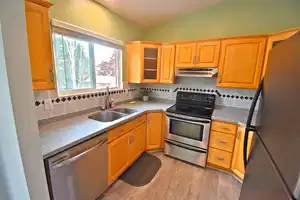 Kitchen with light hardwood / wood-style floors, appliances with stainless steel finishes, tasteful backsplash, vaulted ceiling, and sink