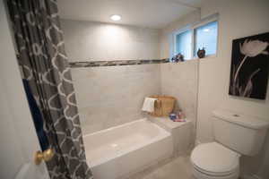 Bathroom with toilet, tile patterned floors, and shower / bath combination with curtain