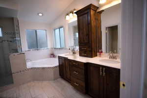 Bathroom with tile patterned flooring, lofted ceiling, separate shower and tub, and vanity