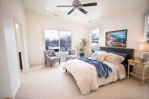 Carpeted bedroom featuring vaulted ceiling, ceiling fan, and multiple windows