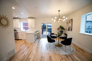 Dining room with light hardwood / wood-style floors, sink, and a notable chandelier