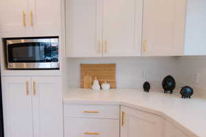 Kitchen featuring decorative backsplash and white cabinetry