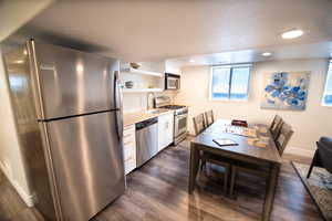 Kitchen with white cabinets, sink, appliances with stainless steel finishes, and dark hardwood / wood-style flooring