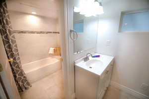 Bathroom with tile patterned floors, shower / bath combo, and vanity