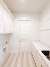 Laundry area with sink, hookup for an electric dryer, and cabinets