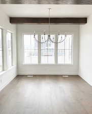 Unfurnished dining area featuring light wood-type flooring, plenty of natural light, and a notable chandelier