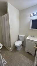 Bathroom featuring a textured ceiling, walk in shower, vanity, and toilet