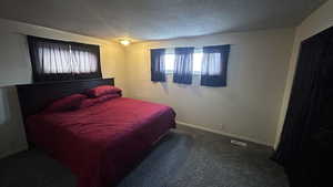 Bedroom featuring a textured ceiling and dark colored carpet