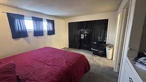 Bedroom featuring a closet, a textured ceiling, and light carpet