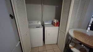 Washroom with washing machine and clothes dryer and light tile patterned floors