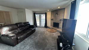 Carpeted living room with a textured ceiling, french doors, and a stone fireplace