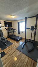 Exercise area featuring wood-type flooring and a textured ceiling