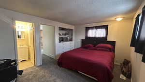 Carpeted bedroom featuring ensuite bath and a textured ceiling