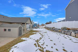 Yard covered in snow with a storage unit and a playground