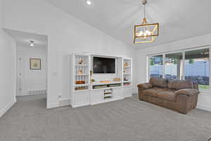 Living room with light carpet, a healthy amount of sunlight, high vaulted ceiling, and a notable chandelier