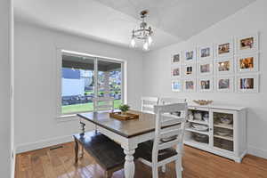 Dining area featuring vaulted ceiling, an inviting chandelier, and hardwood / wood-style floors