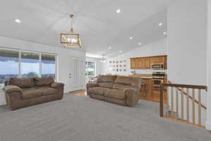 Living room with light carpet, vaulted ceiling, a notable chandelier, and sink