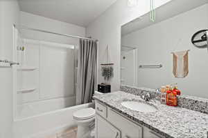 Full bathroom featuring a textured ceiling, tile patterned flooring, vanity, toilet, and shower / bath combo