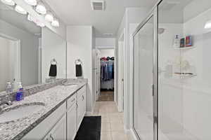 Bathroom with a textured ceiling, walk in shower, vanity, and tile patterned flooring