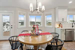 Dining space featuring light wood-type flooring, a notable chandelier, and a healthy amount of sunlight