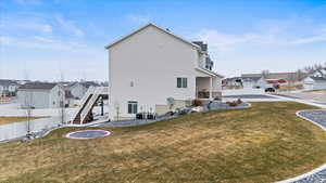 Back of property with a trampoline, central air condition unit, and a yard