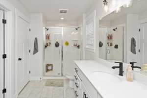 Bathroom featuring toilet, a shower with door, and vanity