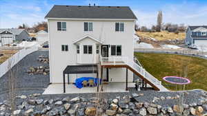 Back of property featuring a wooden deck, a trampoline, a yard, and a patio