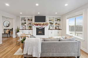 Living room featuring light wood-type flooring and built in features