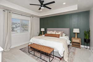 Primary bedroom with a raised ceiling and ceiling fan