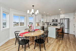 Dining room with light hardwood / wood-style floors, sink, and an inviting chandelier